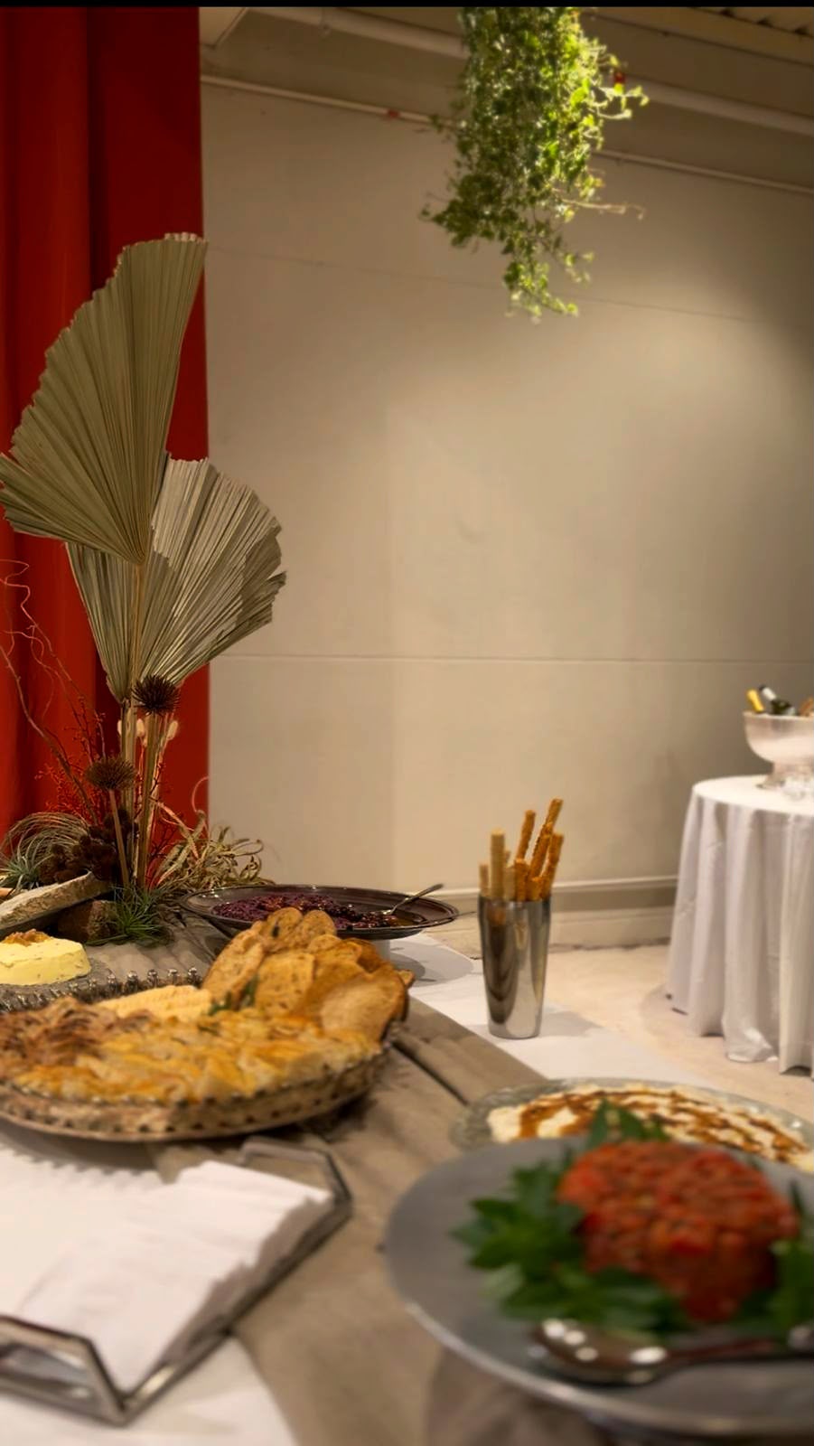Mesa posta do evento com arranjo de folhas secas, pães artesanais, pastas e tartare de tomate.